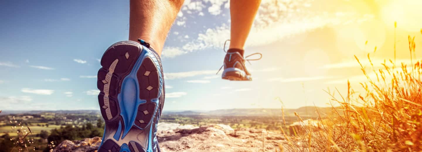 Close-up of a person jogging on a rocky path in the sun, showing how travelers can stay fit outdoors while away from home.