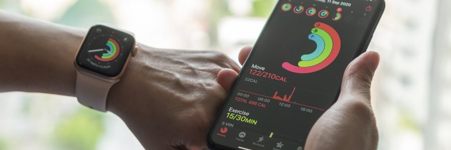 Traveler checks workout progress on a smartwatch and phone, reviewing fitness stats to stay healthy while away from home.
