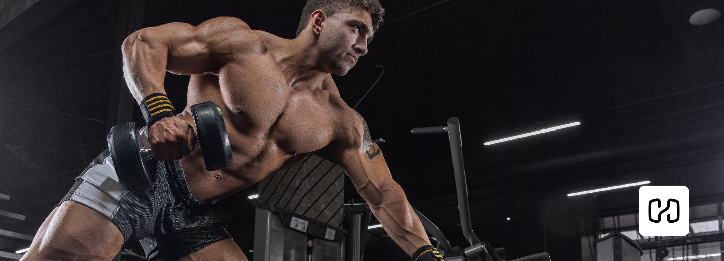 A man lifts a dumbbell in a hotel gym, using the Hevy app, showing how to stay fit while traveling.