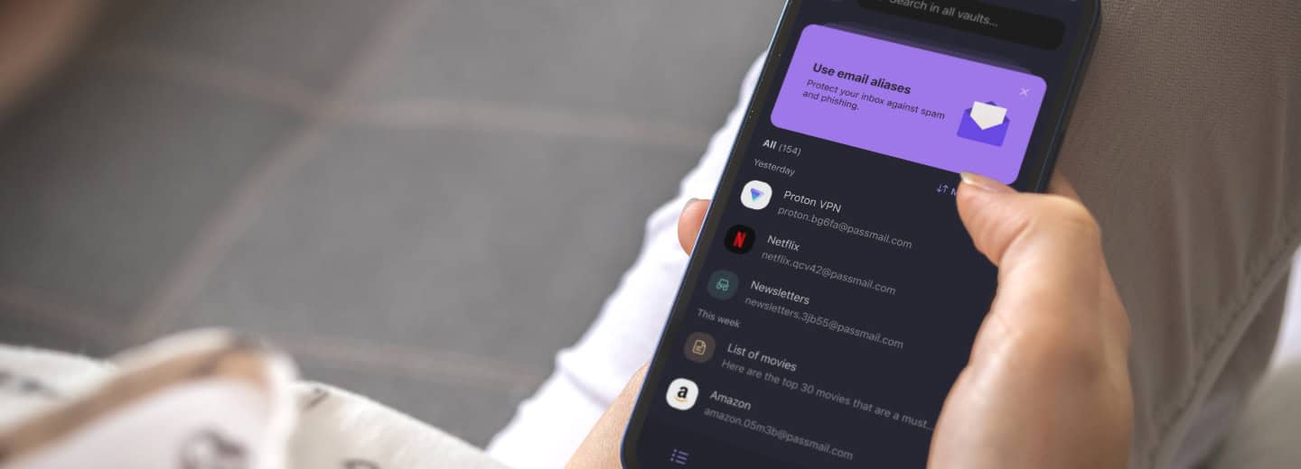Traveler holding a phone and checking a password manager app with saved logins, alongside a purple email alias popup, making it easy to securely book fitness facilities on the go.