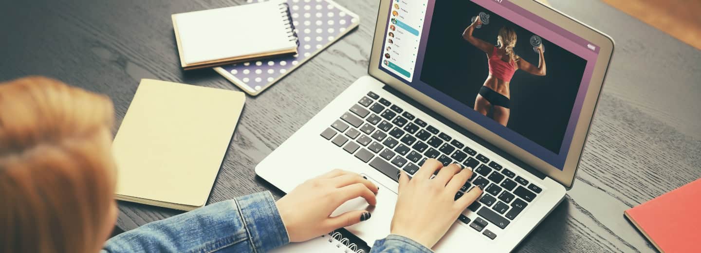 Travel and Fitness Blogger using a laptop to write a blog post; notebooks placed beside the laptop.