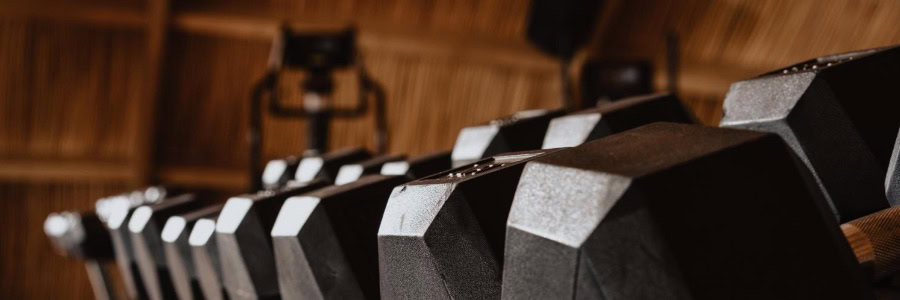 A row of black hexagonal dumbbells in a hotel gym, perfect for guests wanting to stay fit while traveling. Blurred background.