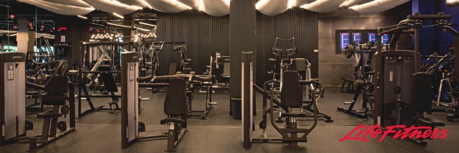 Stay fit while traveling in this modern hotel gym featuring strength machines, ambient lighting, and a visible Life Fitness logo.