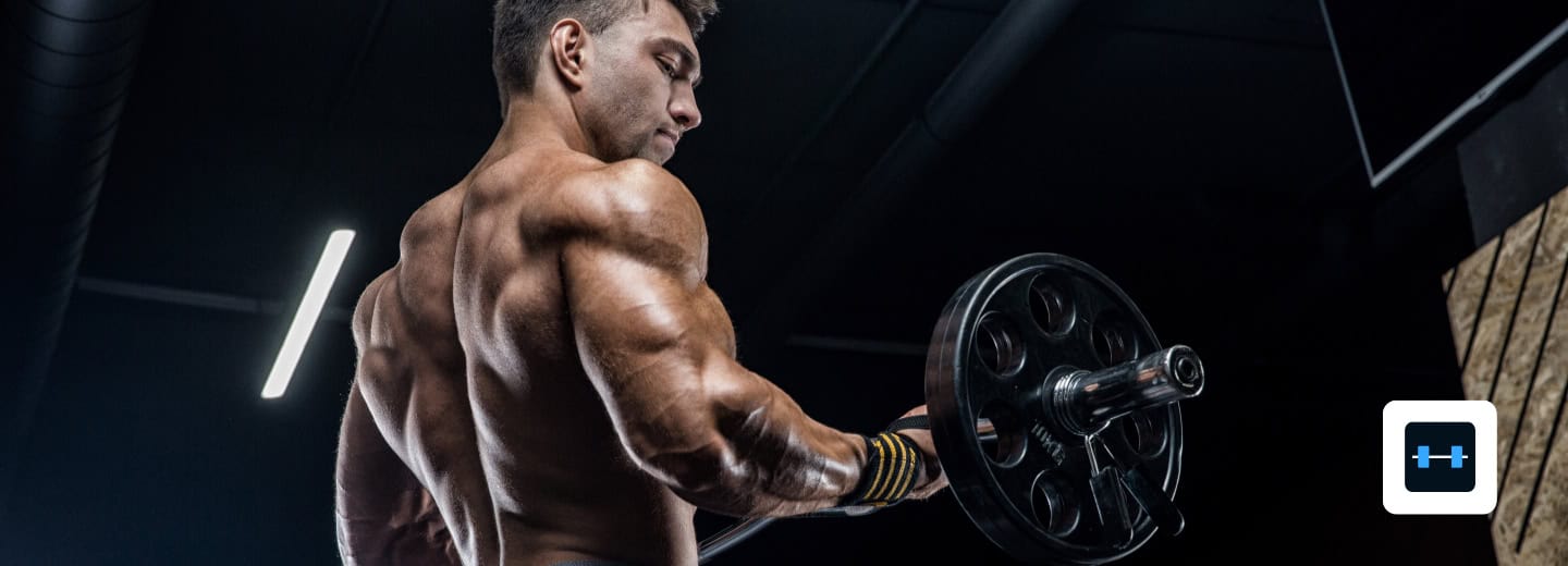 Man lifting a barbell in a gym, promoting strong app, staying fit while traveling at hotels.