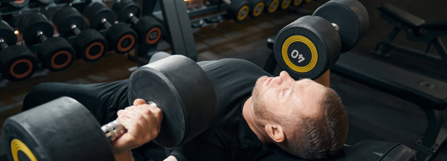 Guest lifting dumbbells on a bench in a hotel gym, showing convenient fitness options for travelers.