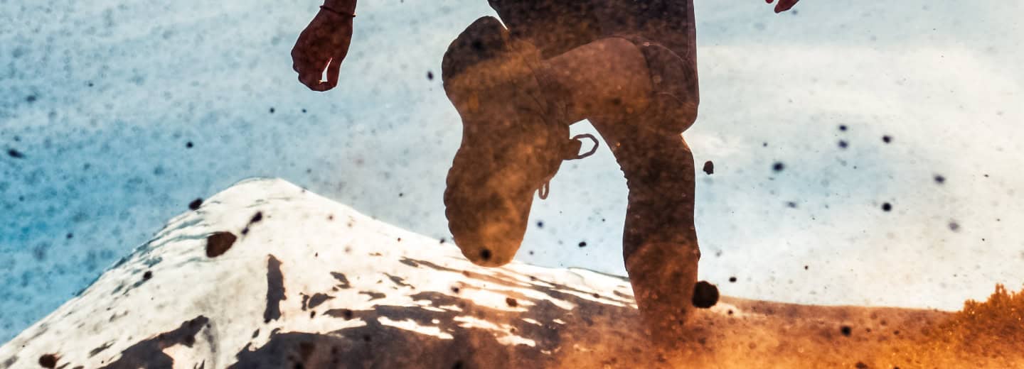 Traveler running energetically up to a snowy mountain, kicking up dirt to stay active and fit during their journey.