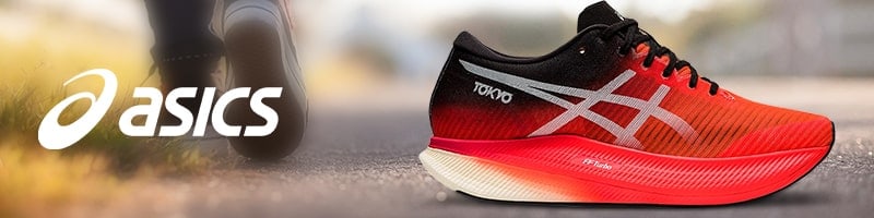 Red ASICS running shoe with white logo and “TOKYO” text, ideal for staying fit while traveling; blurred outdoor background.