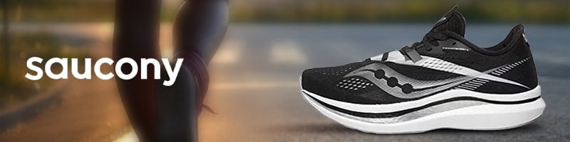 Black Saucony running shoe on a road, highlighting fitness for travelers.